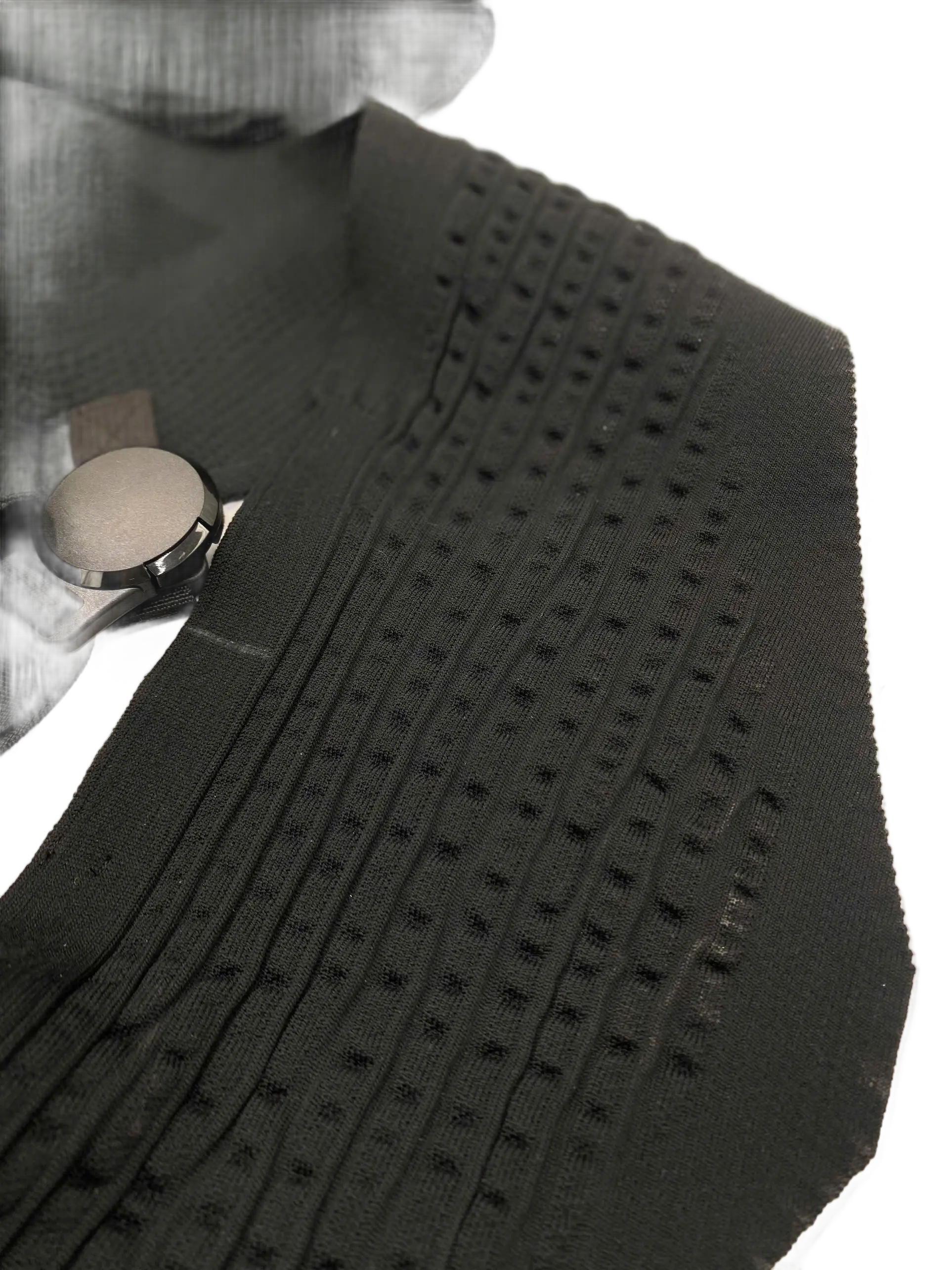 Close-up of the 3D-knitted panel showing raised dot texture and ribbed channels, with magnetic buckle at the edge