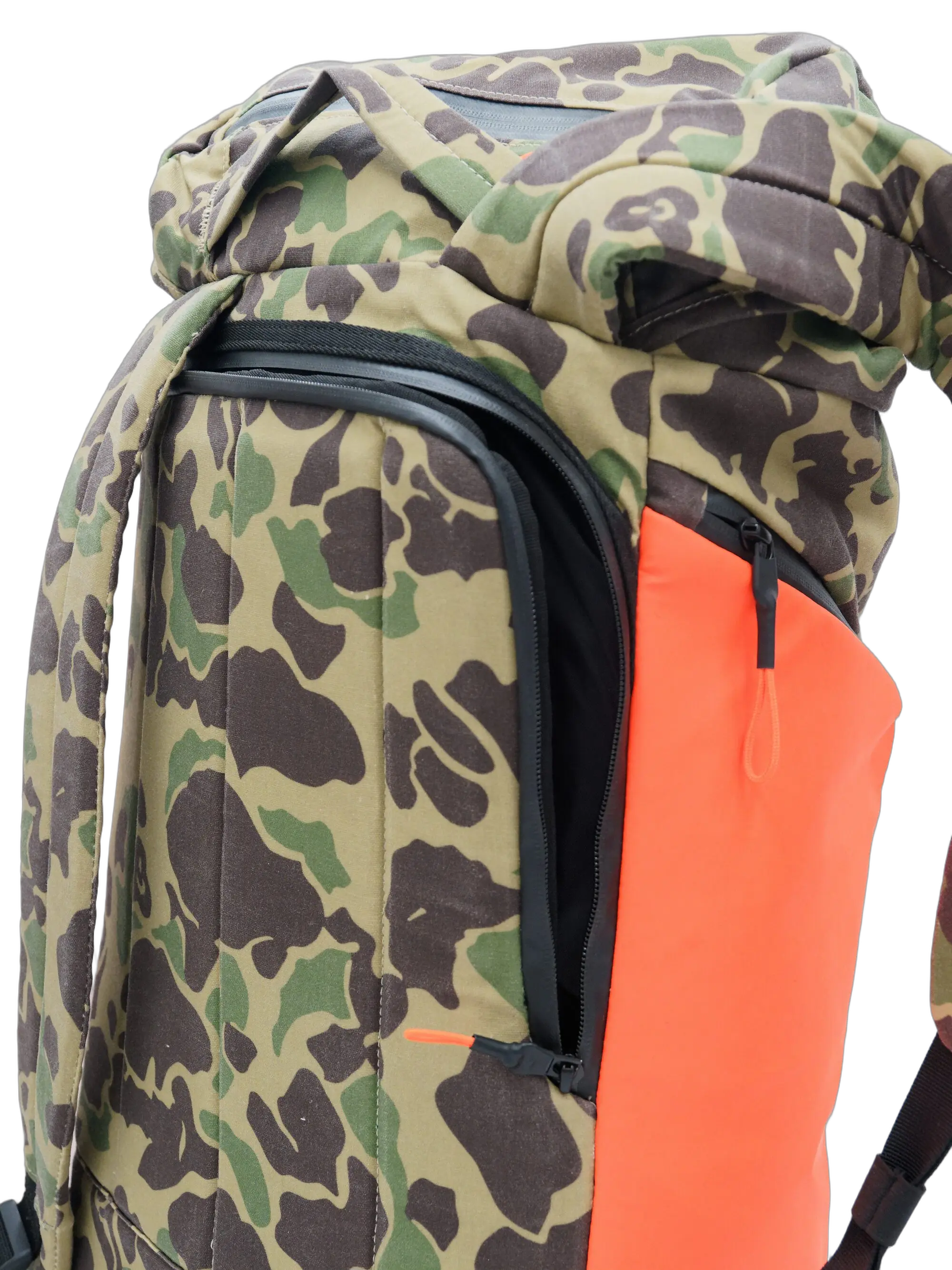 Side close-up of the camo waxed canvas backpack showing the zippered access pocket and bright orange PU side pocket
