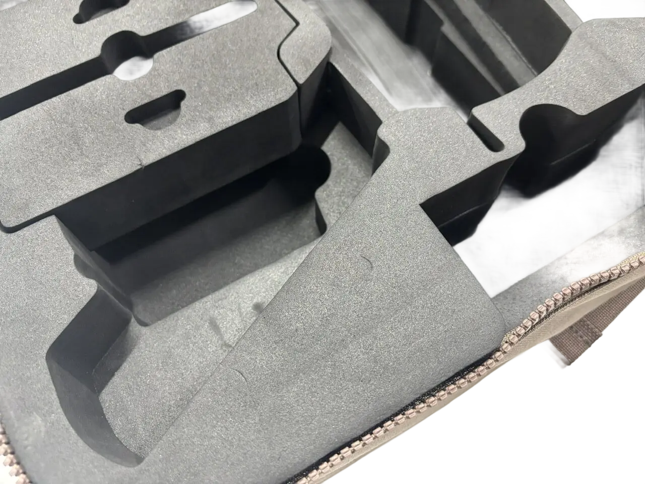 Close-up of dark grey CNC-machined EVA foam insert with precision-cut component cavities for drone equipment