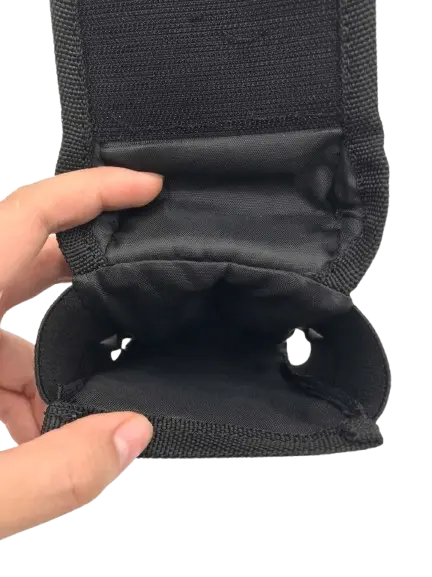 Close-up of the black holster interior showing smooth lined compartment with elastic side cutouts, flap held open by hand