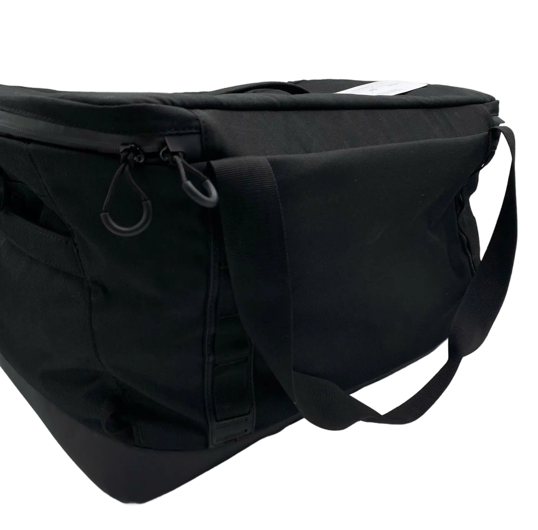 Side view of the large black duffle showing zipper pull, side panel pockets, and shoulder strap attachment hardware