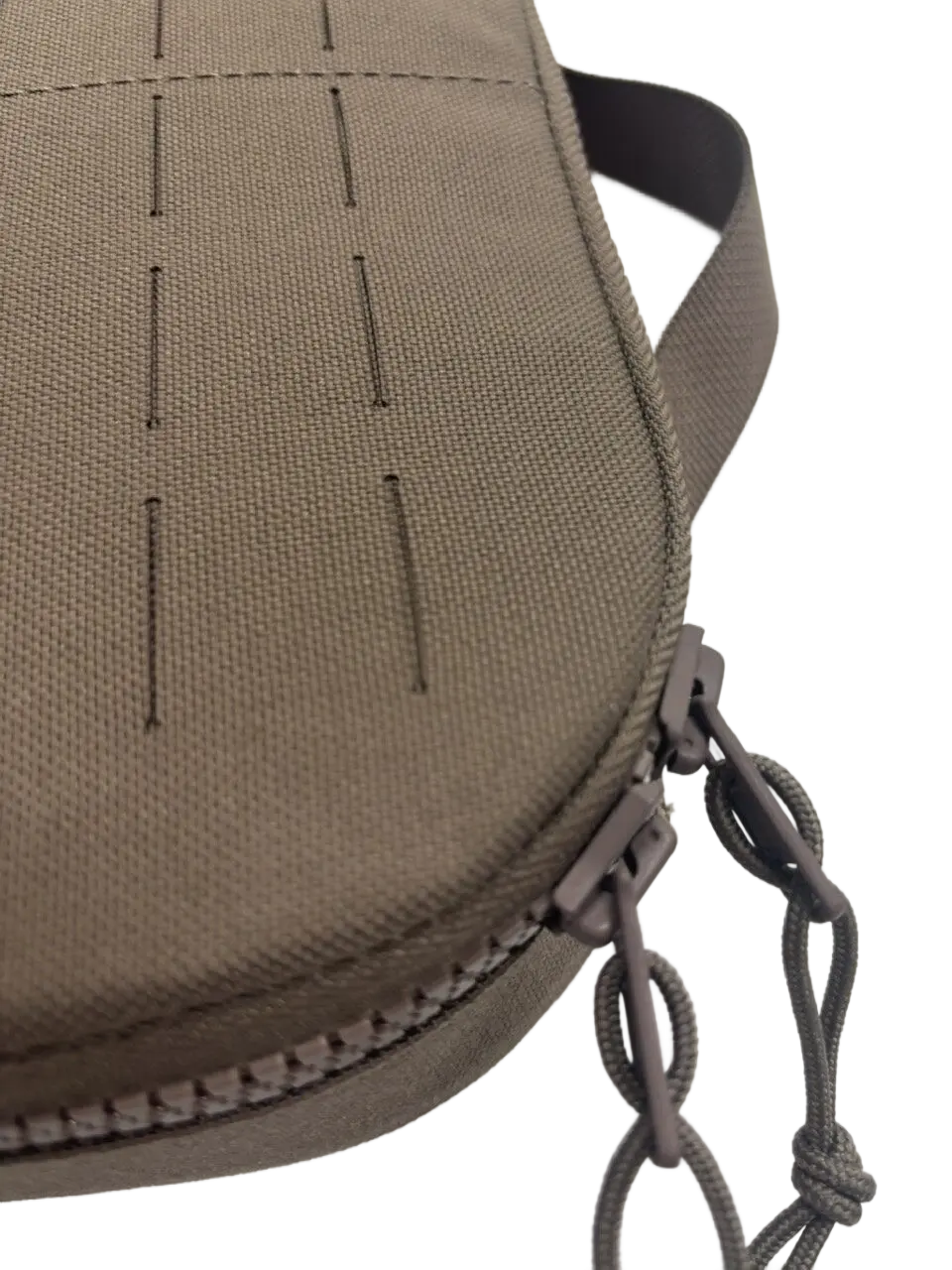 Angled detail of the tan nylon bag showing laser-cut MOLLE grid and dual YKK zipper pullers