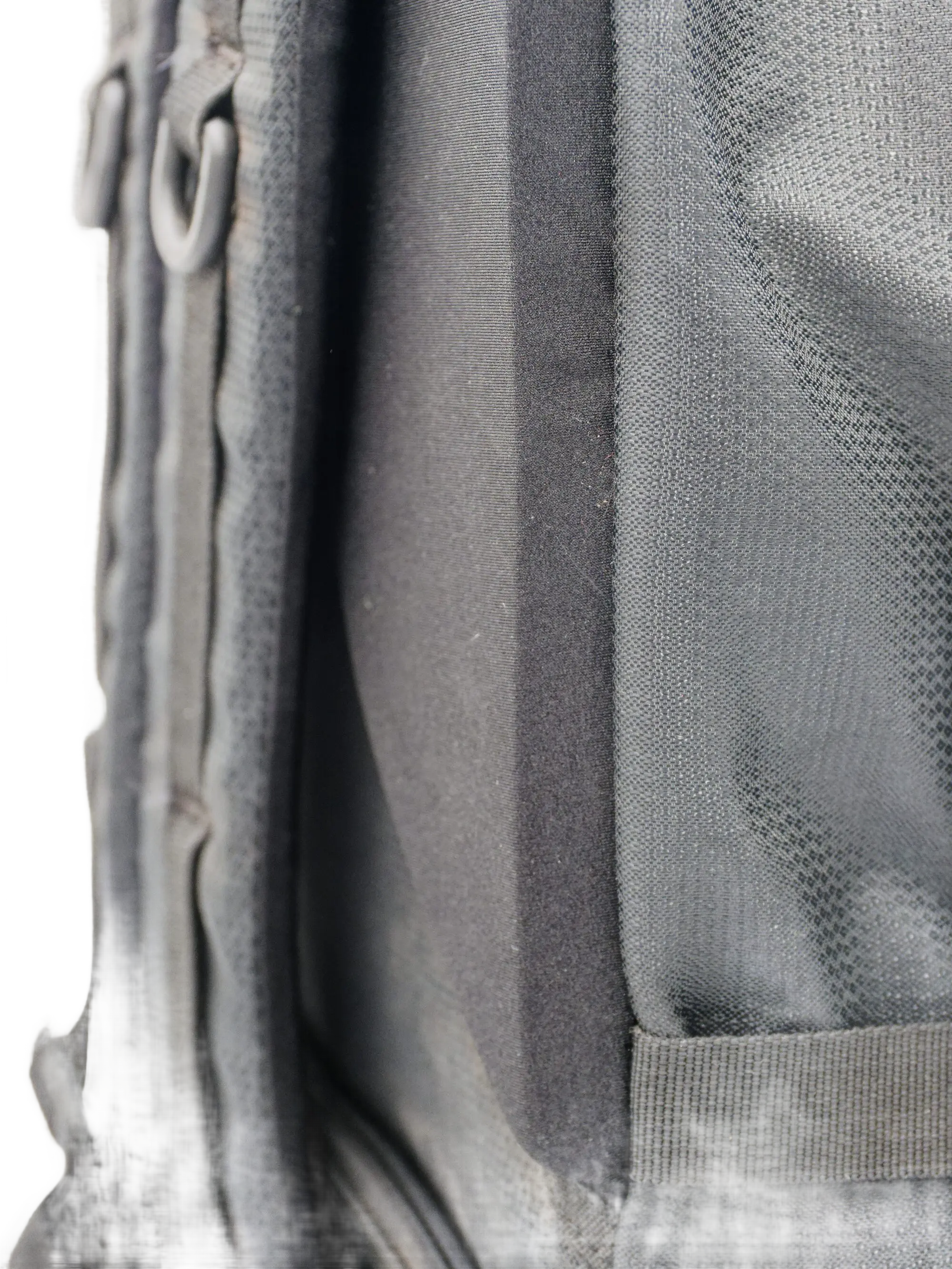 Detail view of the backpack side panel seam showing the grey Dyneema fabric edge stitching and mesh back panel