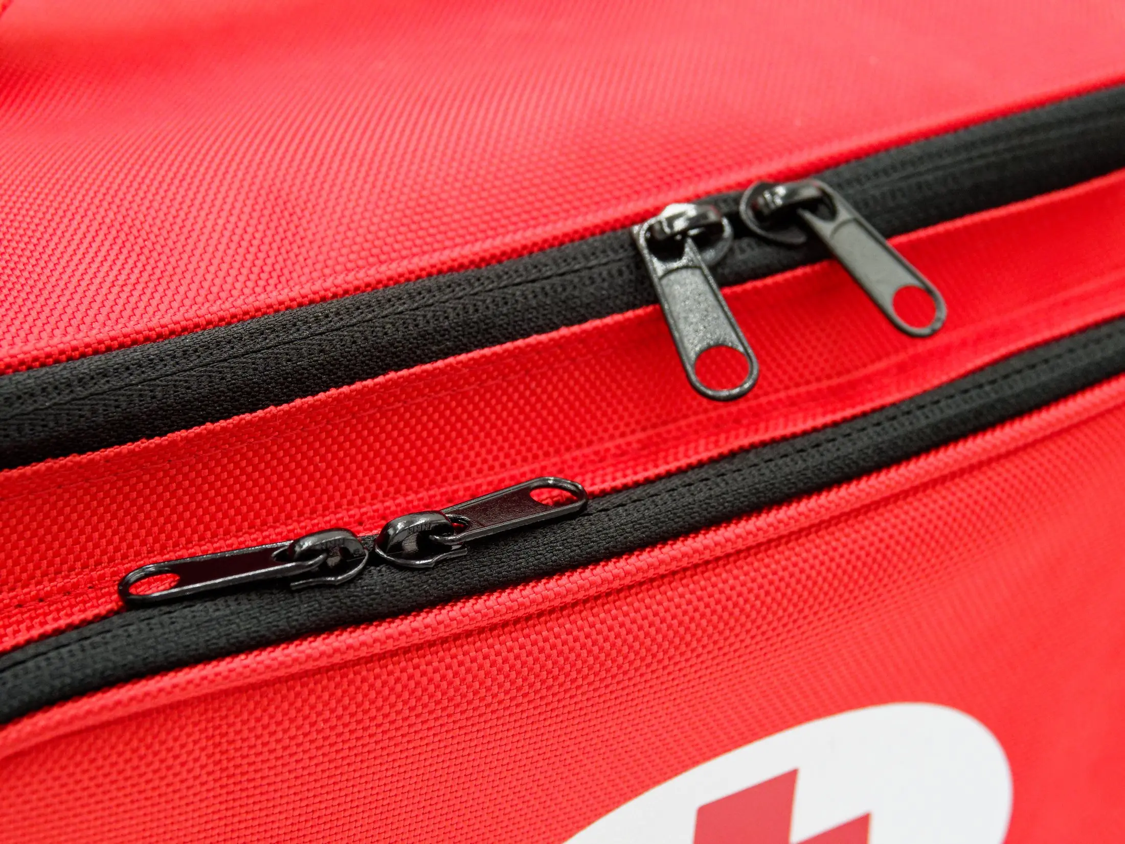 Close-up of the double-zip top closure on the red first aid bag with black zipper tape and metal zipper pulls