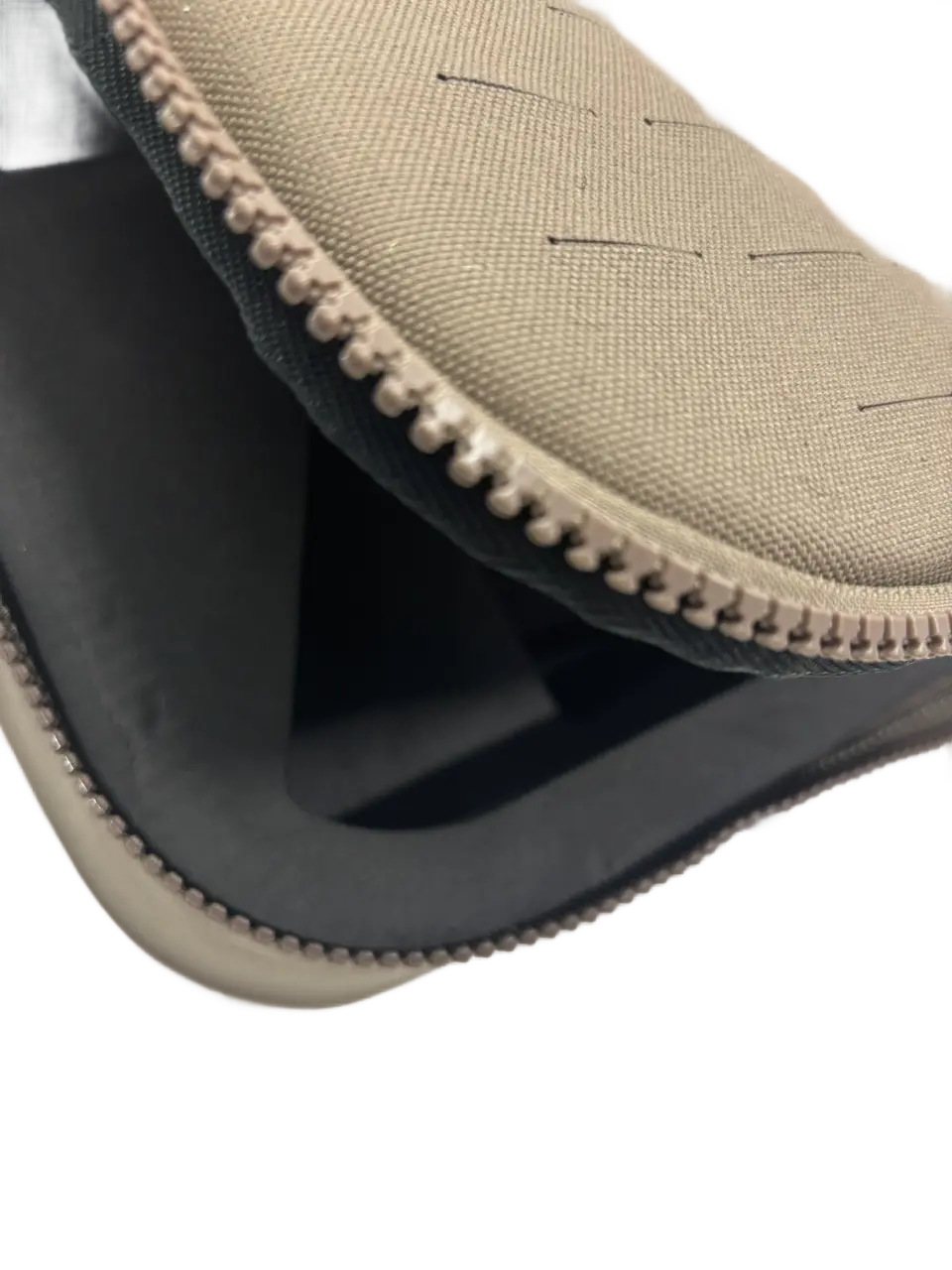 Detail of tan nylon bag corner showing reinforced chain-stitched binding and EVA foam insert edge