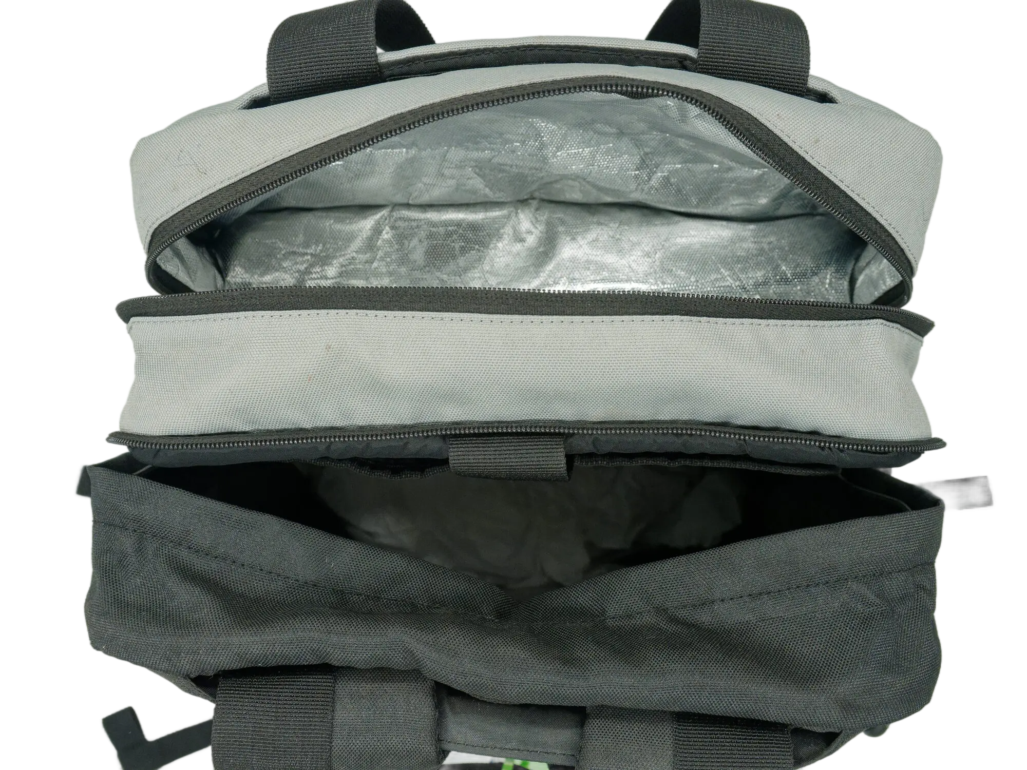 Open top zip pocket viewed from above showing a silver-toned fabric interior lining inside the grey panel