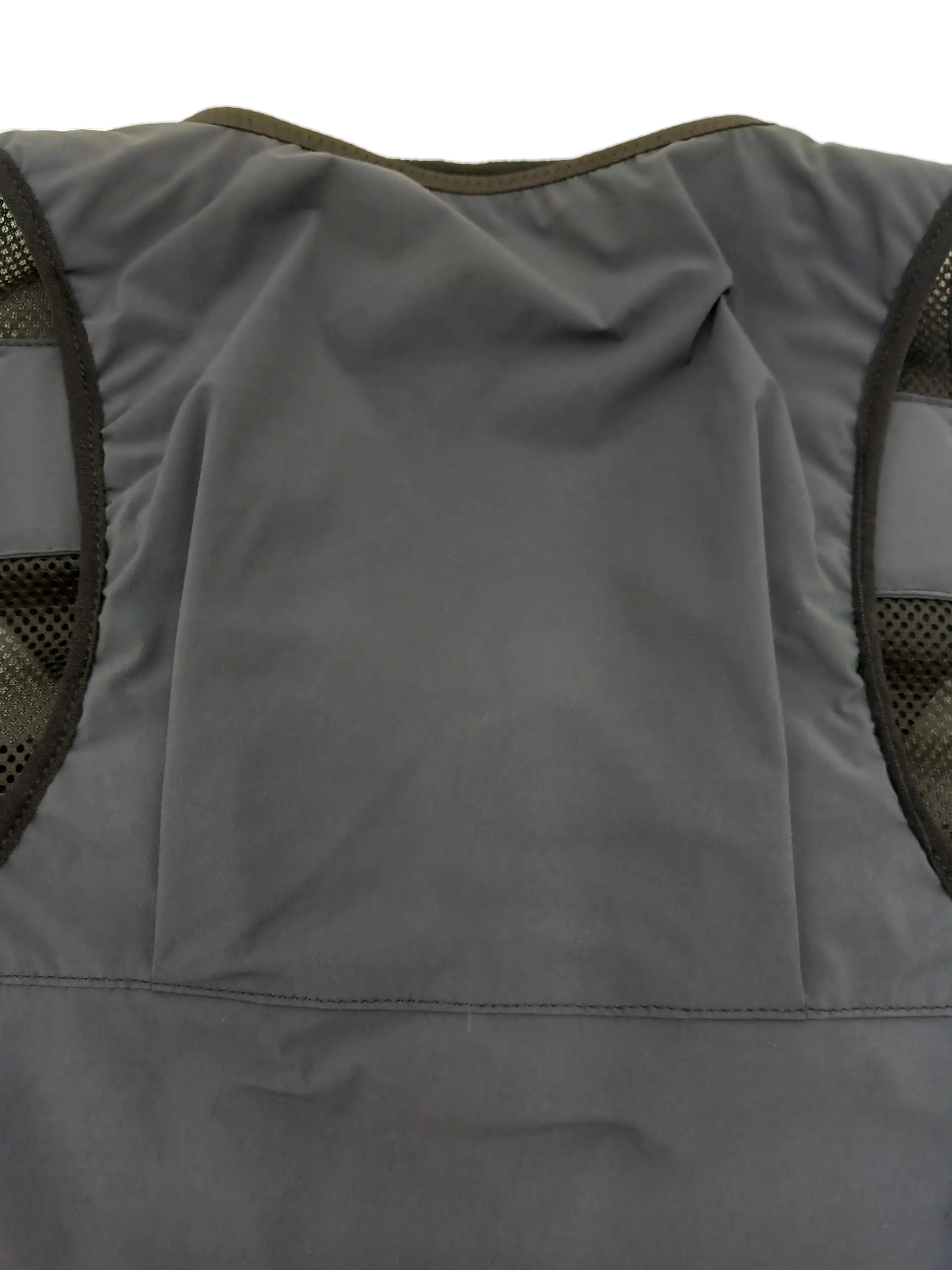 Interior rear panel of the trail running vest showing the flat grey storage compartment lining and mesh side sections