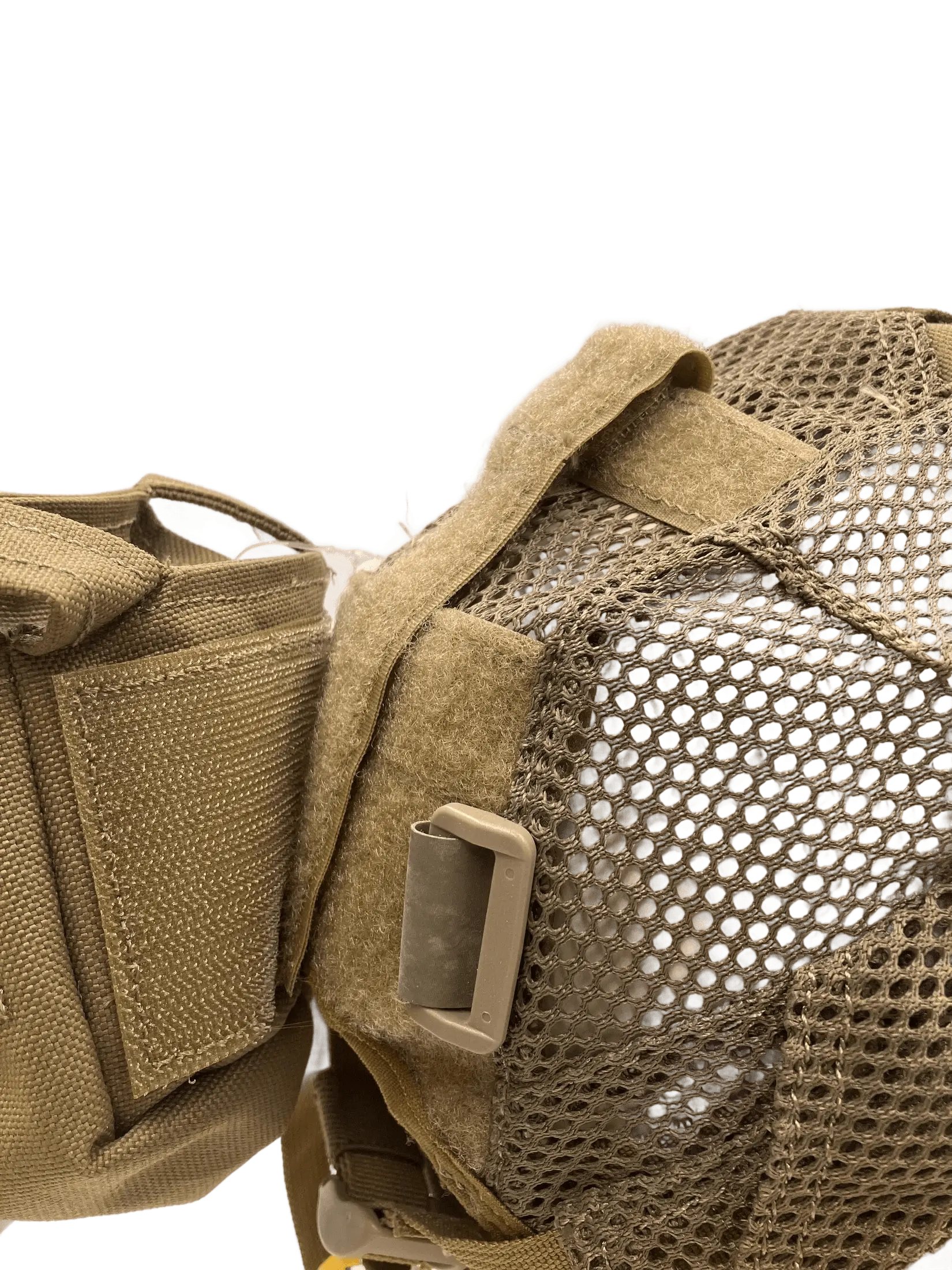 Close-up of the rear lateral attachment point showing tan Cordura panel, velcro flap, and hexagonal mesh texture