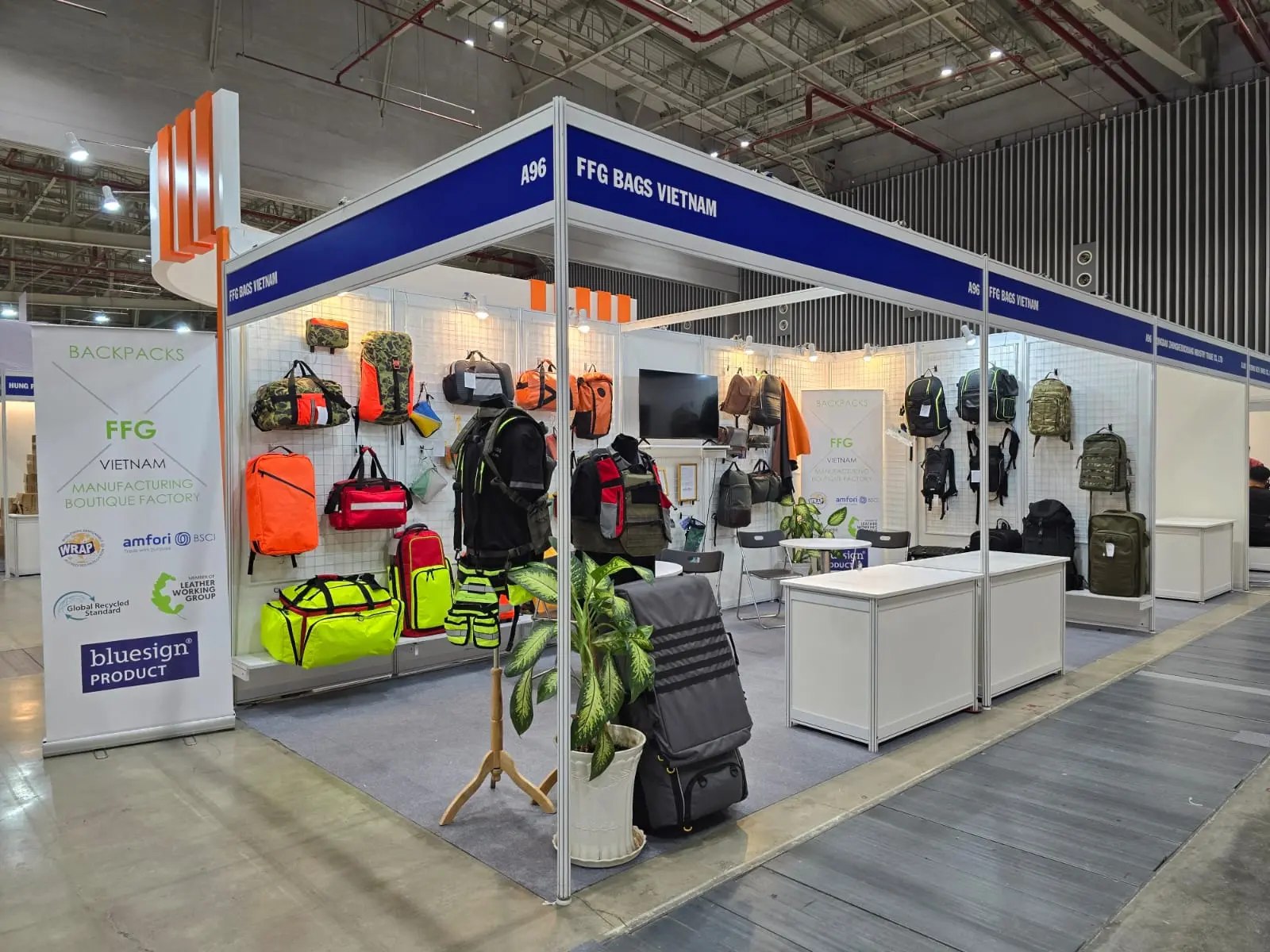 Wide view of FFG Bags exhibition booth with navy and orange signage, tactical backpacks on display walls