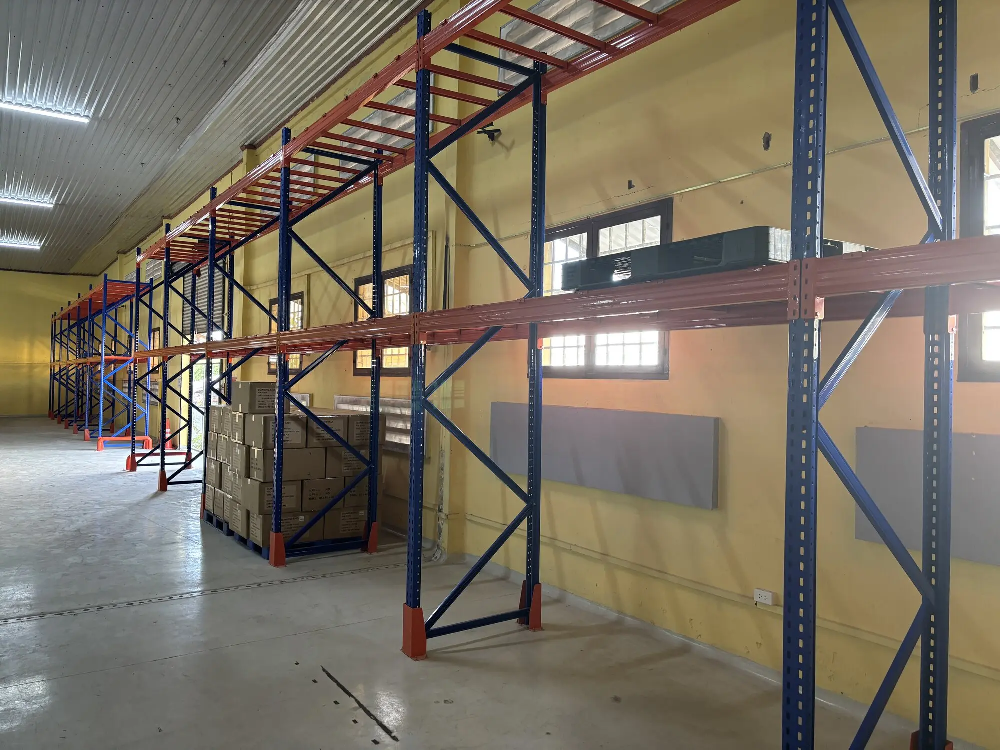 Industrial metal stacking racks with red and blue frame structure in empty warehouse space ready for inventory