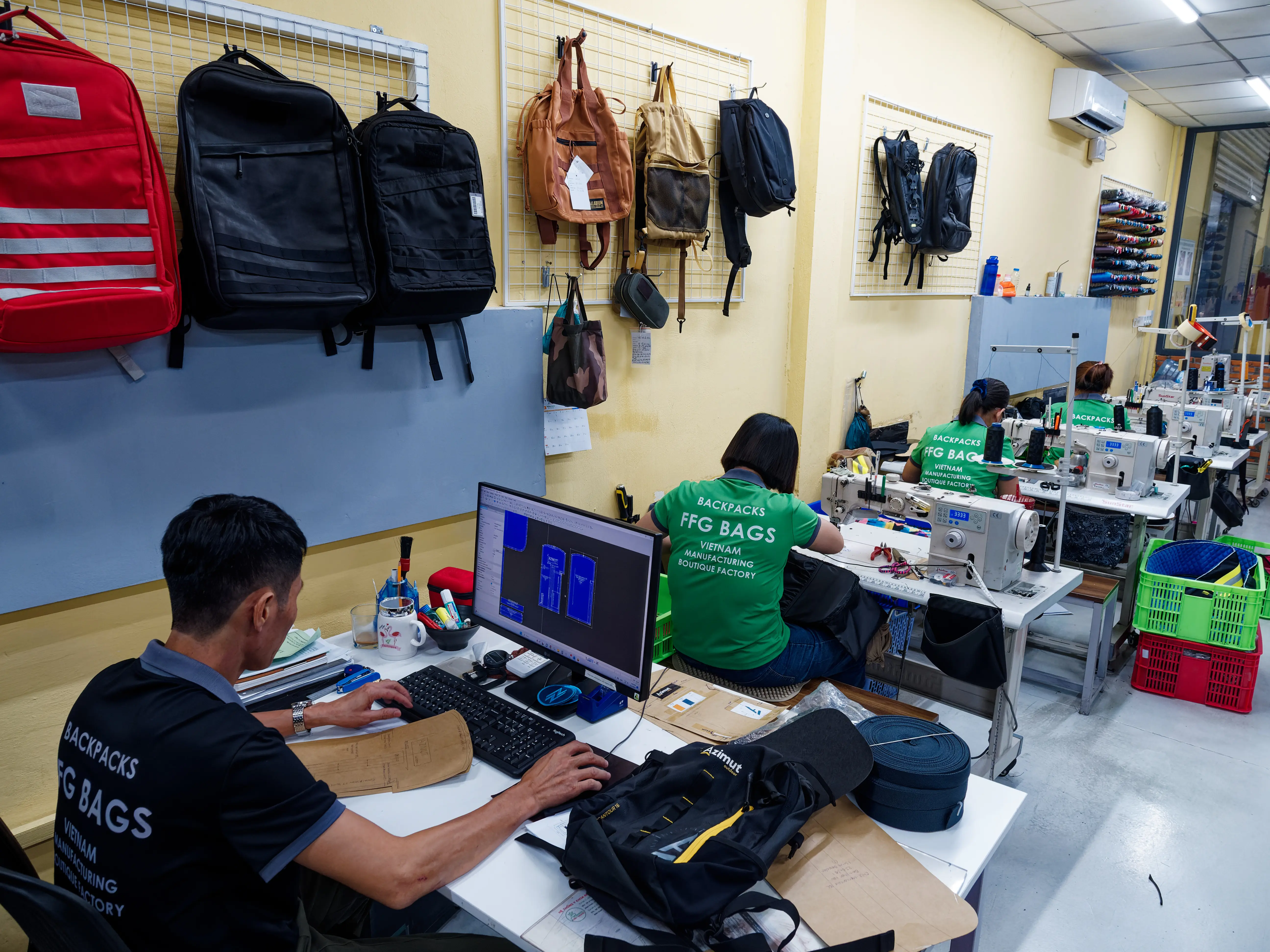 FFG Bags pattern room with backpack samples, digital pattern work and sample sewing stations used during custom bag development