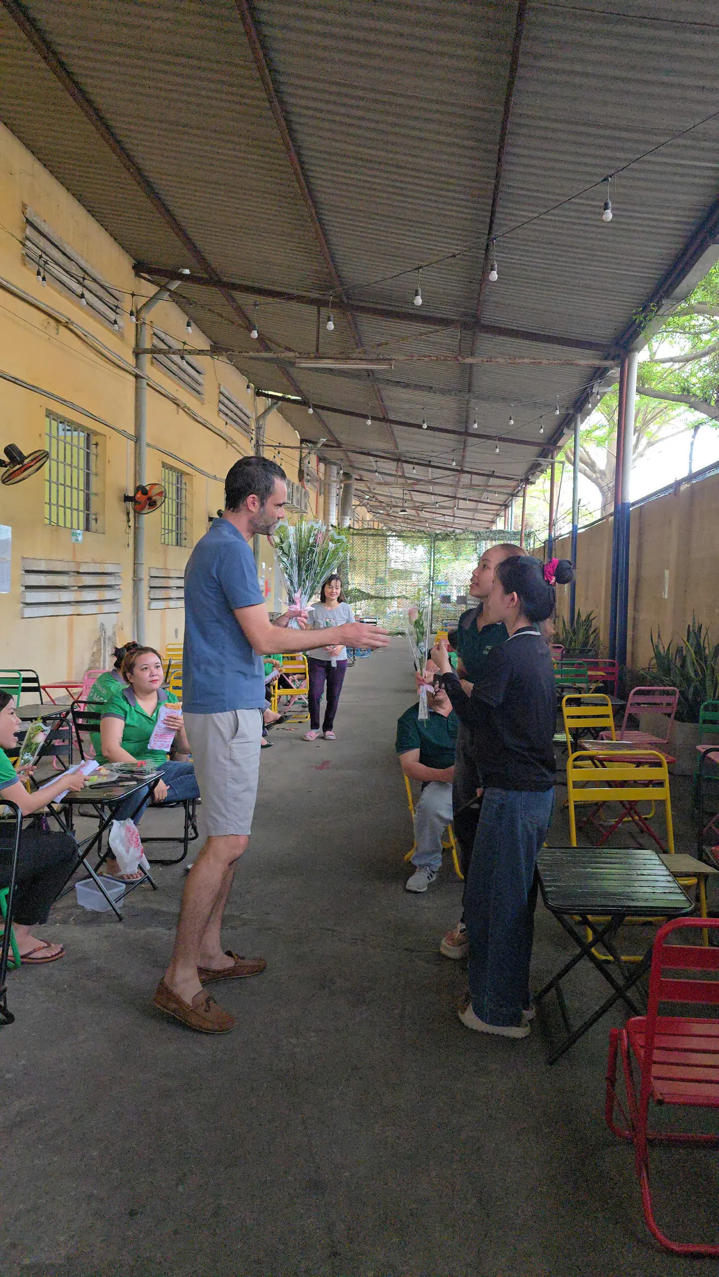 FFG Bags women employees in green shirts conversing under covered outdoor area during celebration