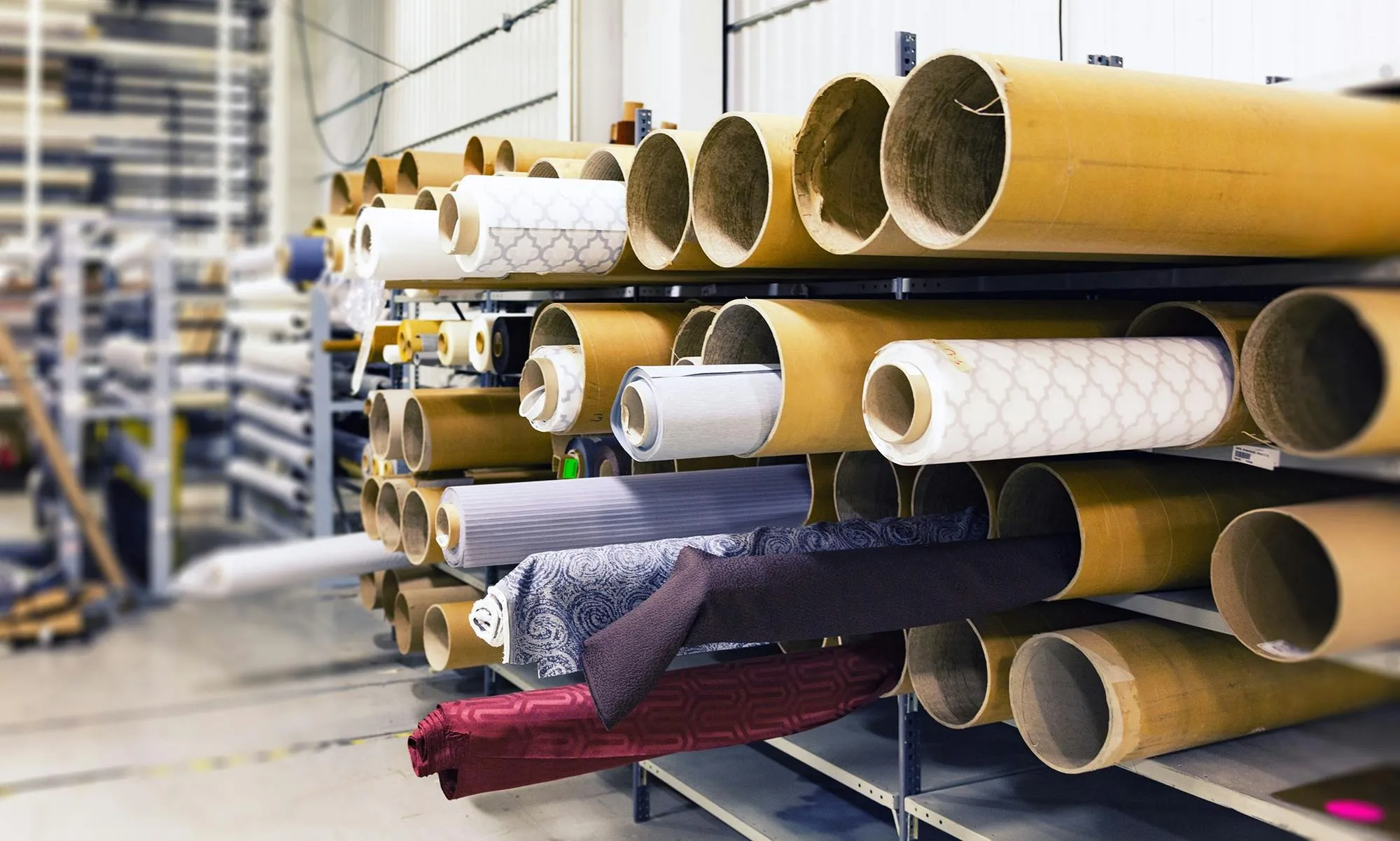 Rows of fabric rolls stored in a textile warehouse, illustrating technical material sourcing for bag manufacturing