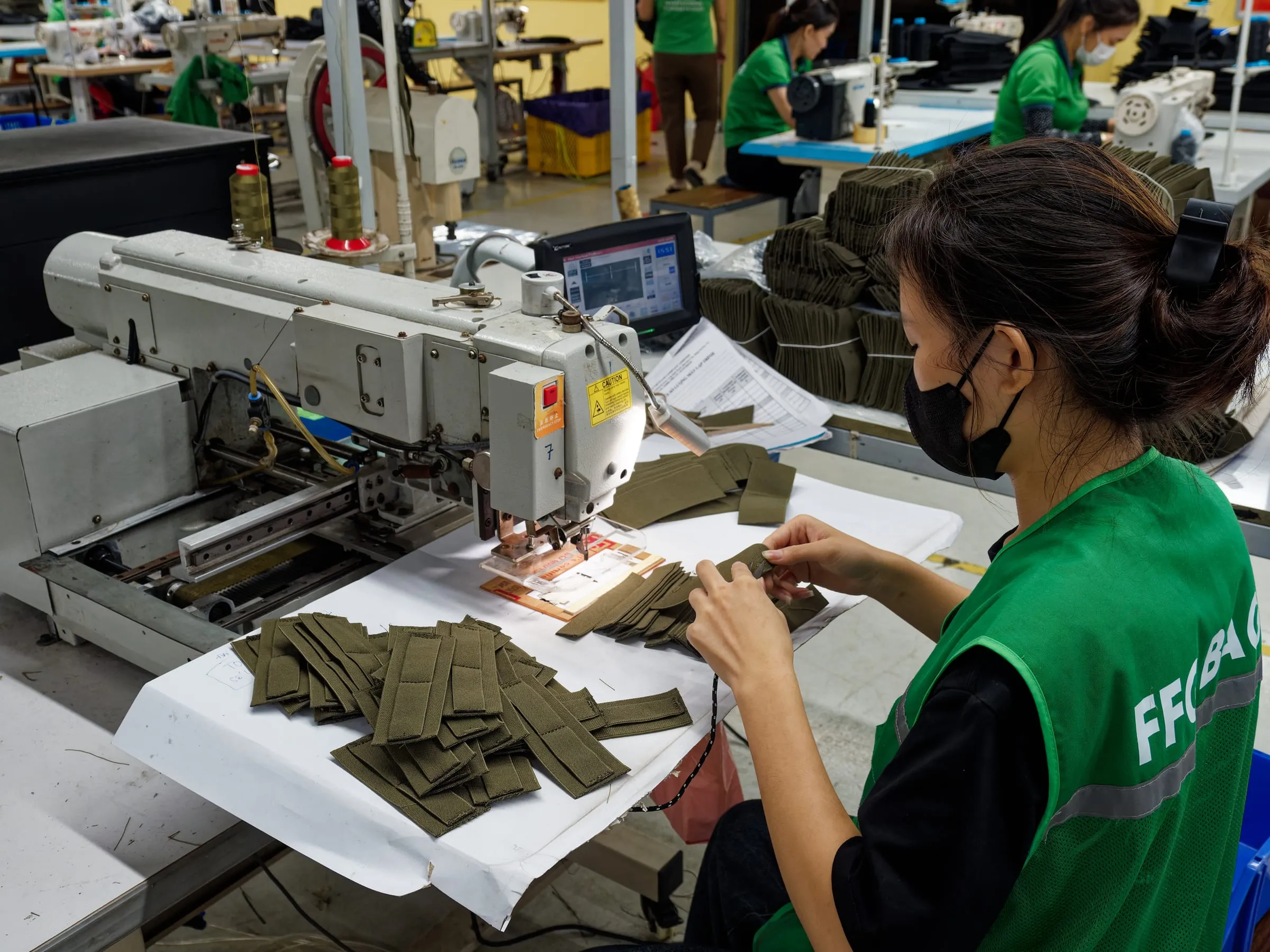 FFG Bags operator stitching green webbing components at a sewing station